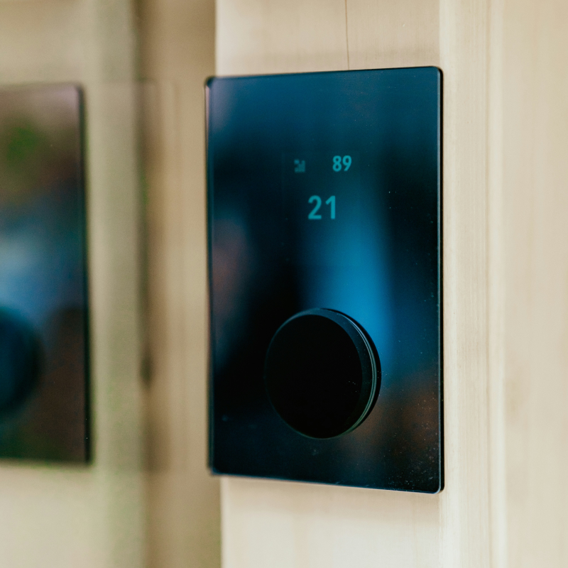 thermostat connecté noir mural avec écran tactile affichant la température et un bouton rotatif.