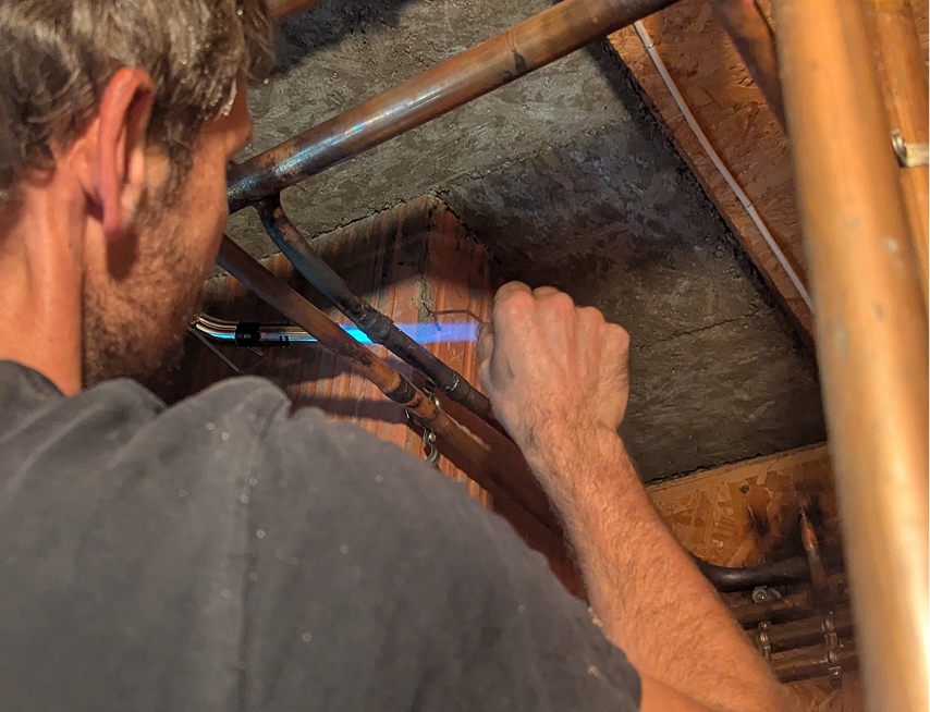 Jérémy fait de la brasure sur des tuyaux en cuivre