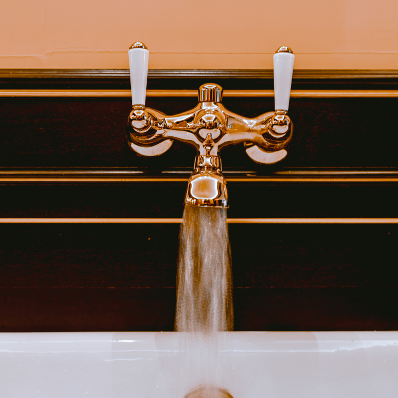 Robinet chromé avec eau chaude sanitaire qui coule dans un lavabo